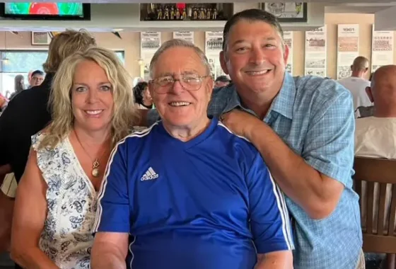 Terri sitting and smiling with 2 other men